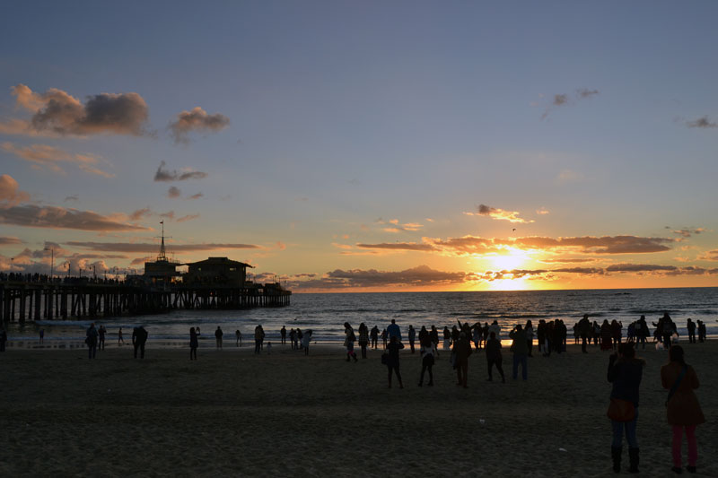 Ludzie zebrani na plaży w Santa Monica podczas zachodu słońca