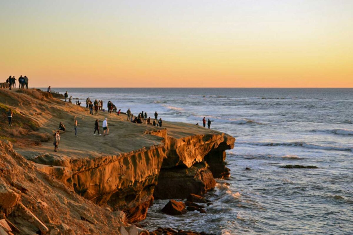Zachód słońca nad Sunset Cliffs w San Diego - widok na skaliste wybrzeże i ocean podczas złotego zachodu słońca, z charakterystycznymi falami i skałami oświetlonymi przez ostatnie promienie słońca.
