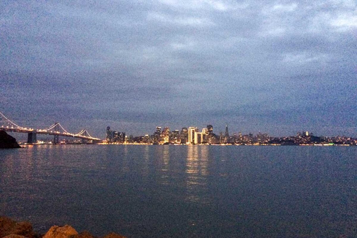 Veduta di San Francisco al tramonto con il profilo della città e il ponte in lontananza.