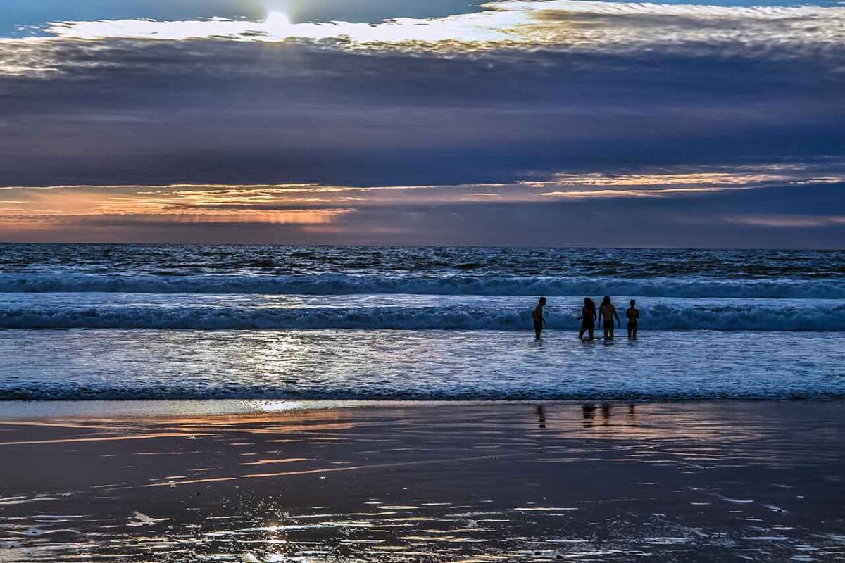 Ludzie na plaży przy zachodzie słońca