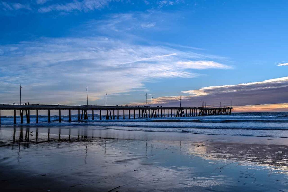 Venice Beach w Los Angeles - widok na molo ze spacerującymi ludźmi na tle rozległego oceanu.