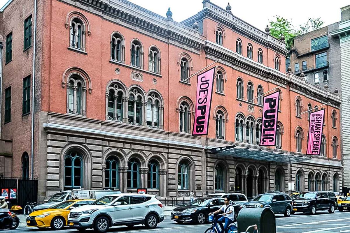 Facciata storica del Public Theater a New York con banner colorati.