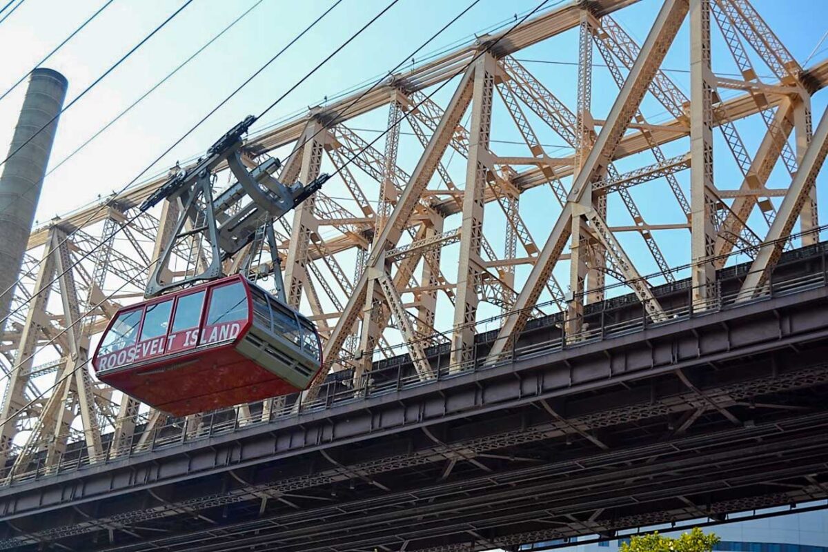 La Roosevelt Island Tramway in volo sopra l'East River con lo skyline di Manhattan sullo sfondo.