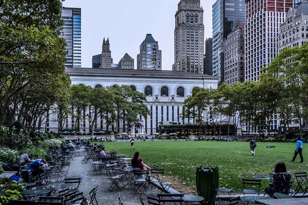Zielony Bryant Park z przekątną alejką i drapaczami chmur w tle