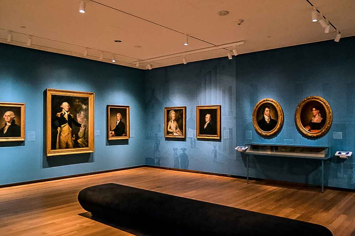 Wnętrze sali muzeum z portretami na niebieskich ścianach
