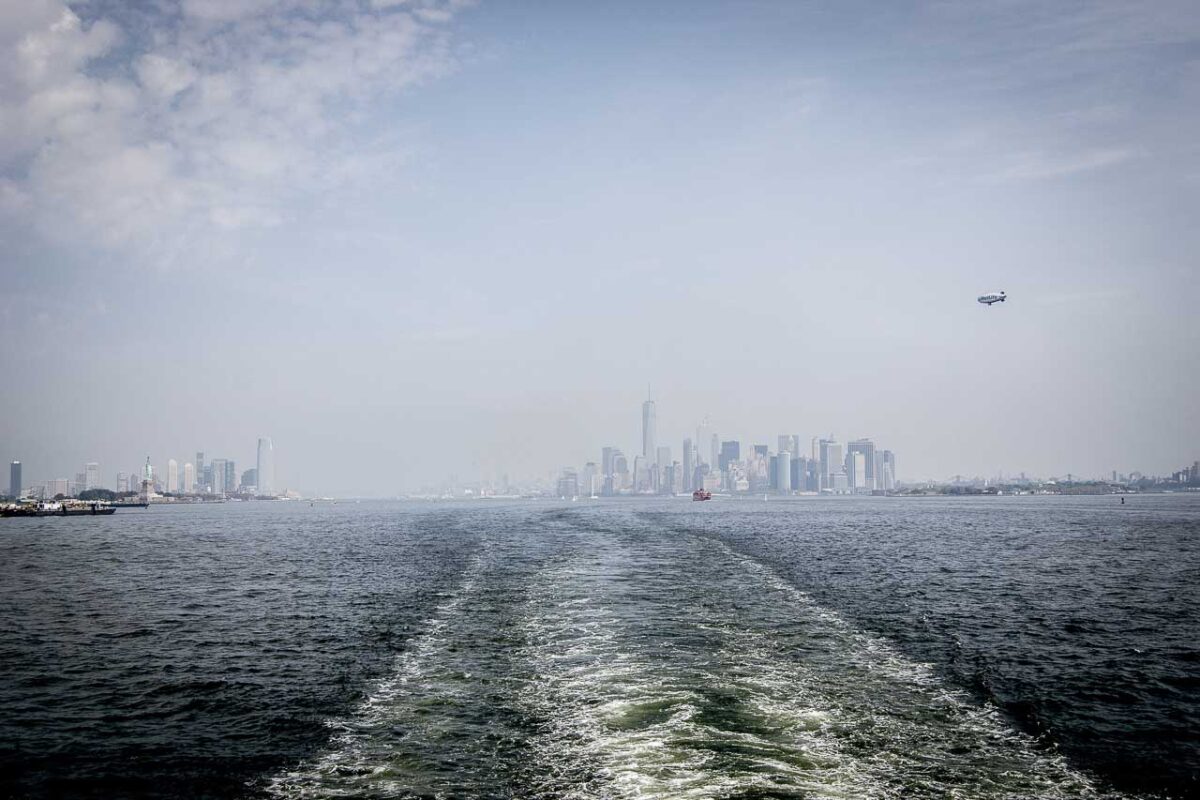 Widok na oddalające się wieżowce Nowego Jorku w tle, z wodami Upper New York Bay na pierwszym planie, podczas rejsu na Staten Island.