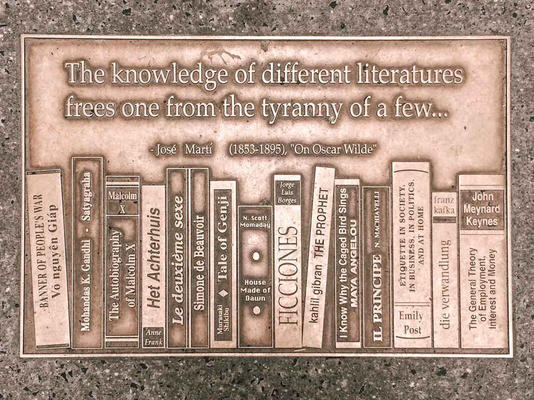 Brązowa płyta z cytatem o literaturze oraz reliefem półki z książkami