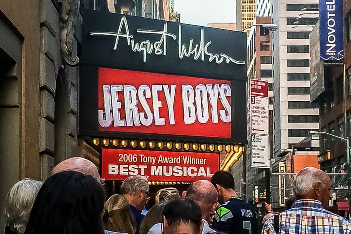 Fasada teatru z afiszem Jersey Boys, grupa widzów przed wejściem