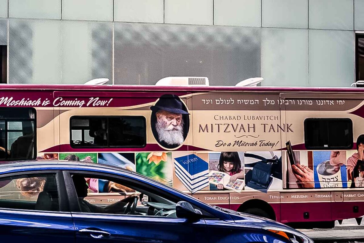 Kolorowy autobus z napisem Mitzvah Tank na tle miejskiego ruchu