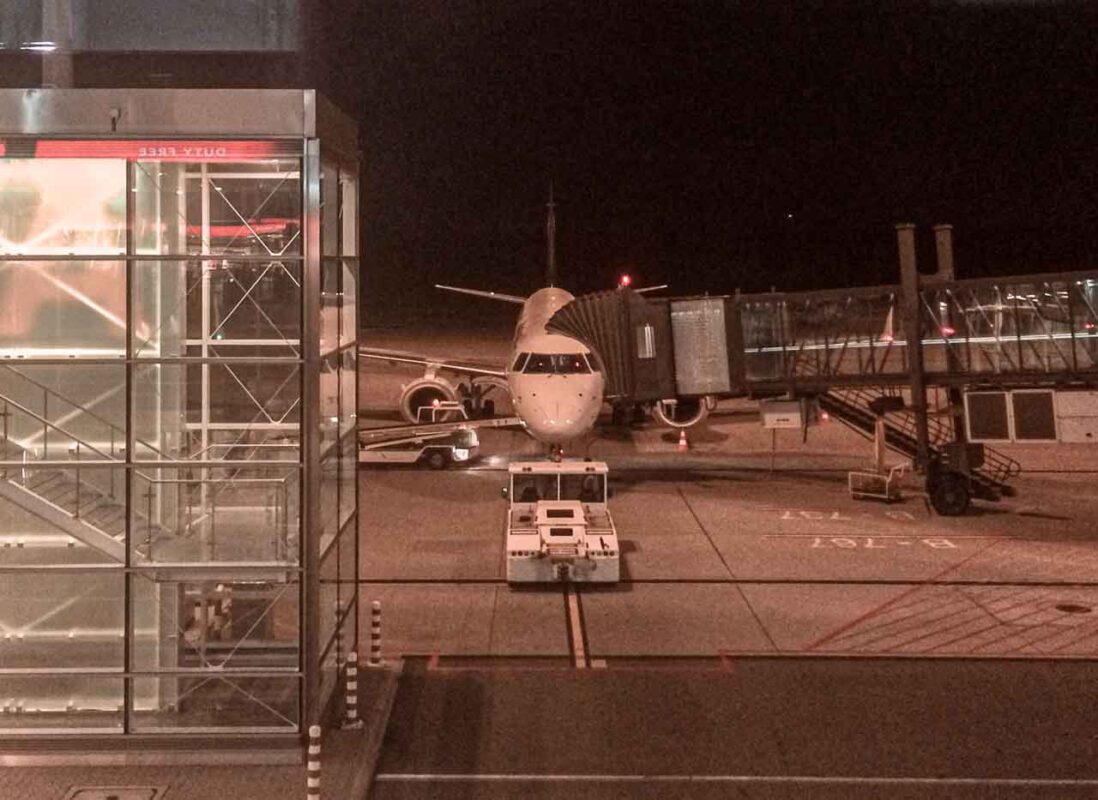 Un aereo parcheggiato sulla pista dell'aeroporto di Breslavia (Wrocław) illuminata di notte.