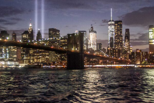Most Manhattan rozświetlony latarniami, odbijającymi się w wodzie
