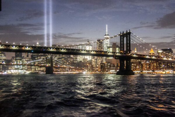 Panorama oświetlonego Manhattan Bridge i miasta nocą widziana z wody