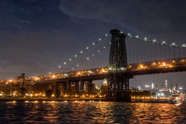 Most Manhattan nocą w pełnej iluminacji, blaski wody