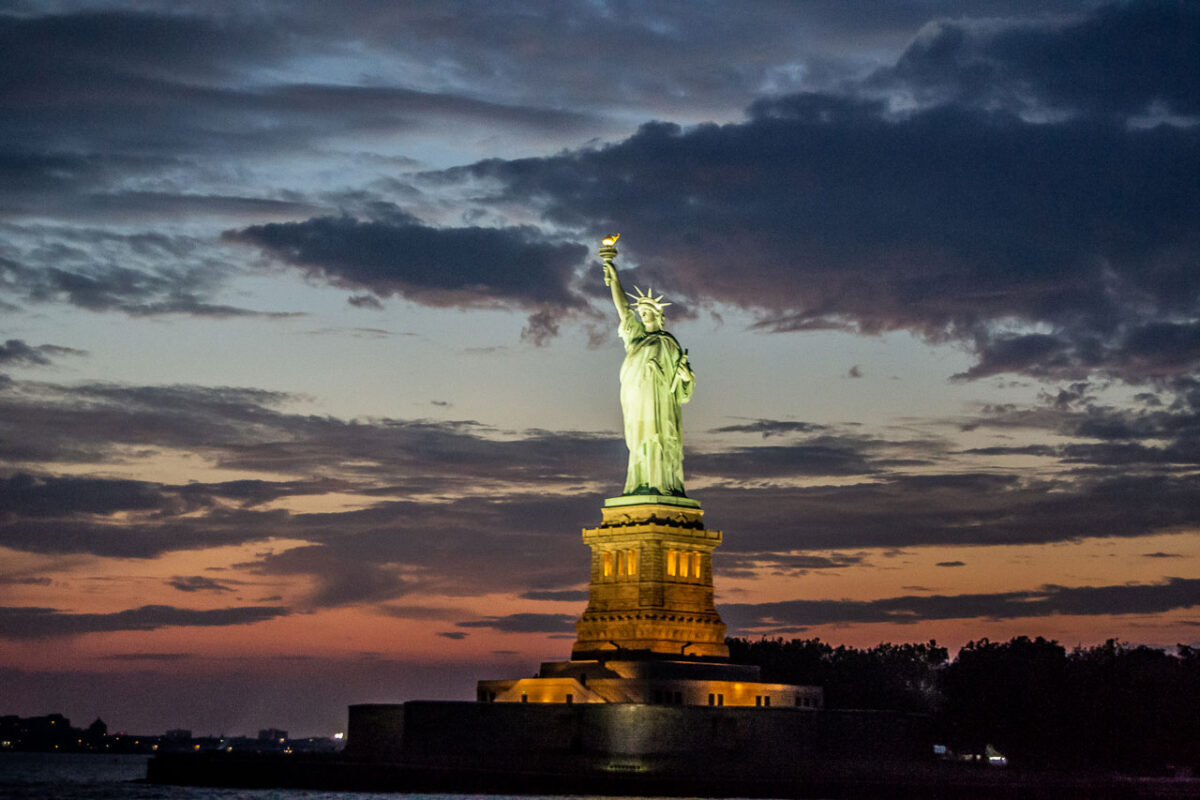 La Statua della Libertà sullo sfondo di un pittoresco cielo serale e dell'acqua.