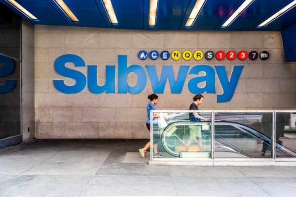 Niebieski napis Subway przy wejściu do stacji metra w Nowym Jorku