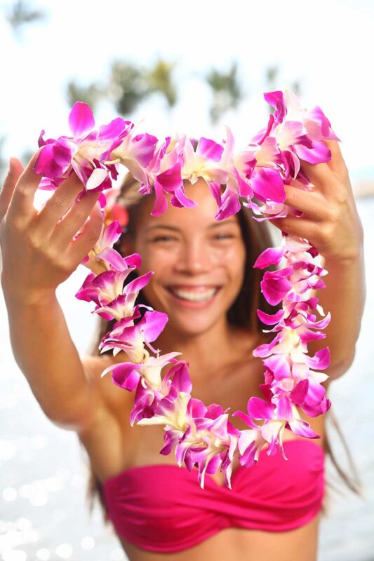 Una donna hawaiana che mostra con orgoglio una ghirlanda di fiori tradizionali (Lei).