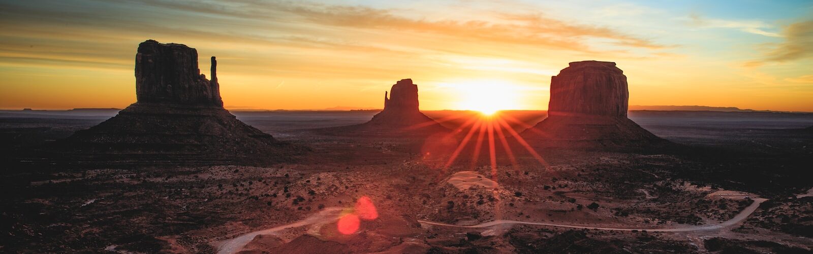 the sun is setting over a desert landscape