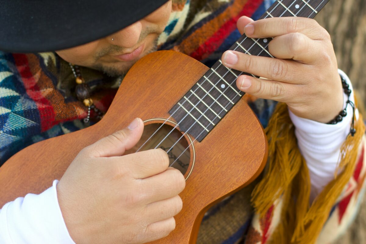 Un musicista che suona con passione un ukulele marrone.