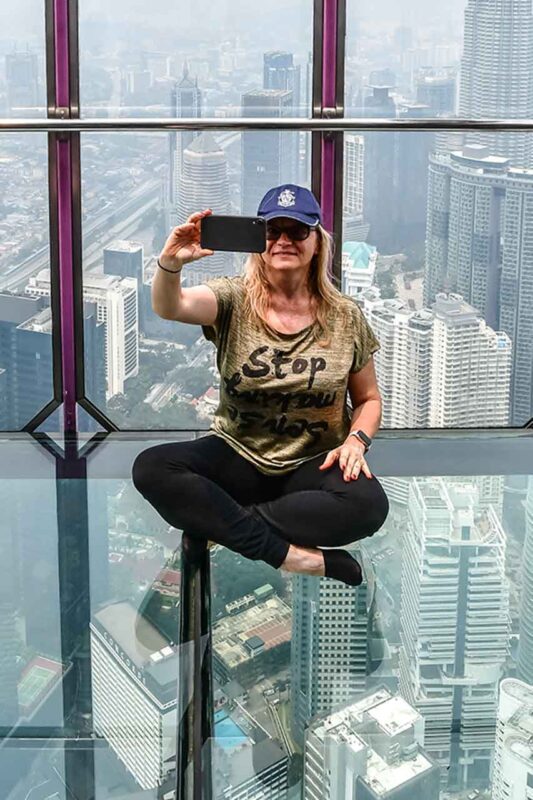 Osoba robiąca selfie na tarasie widokowym KL Tower z panoramą Kuala Lumpur w tle