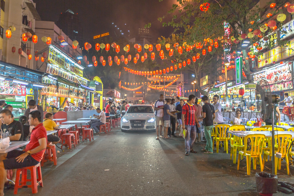 Vista notturna della via Jalan Alor a Kuala Lumpur, piena di luci e bancarelle di cibo.