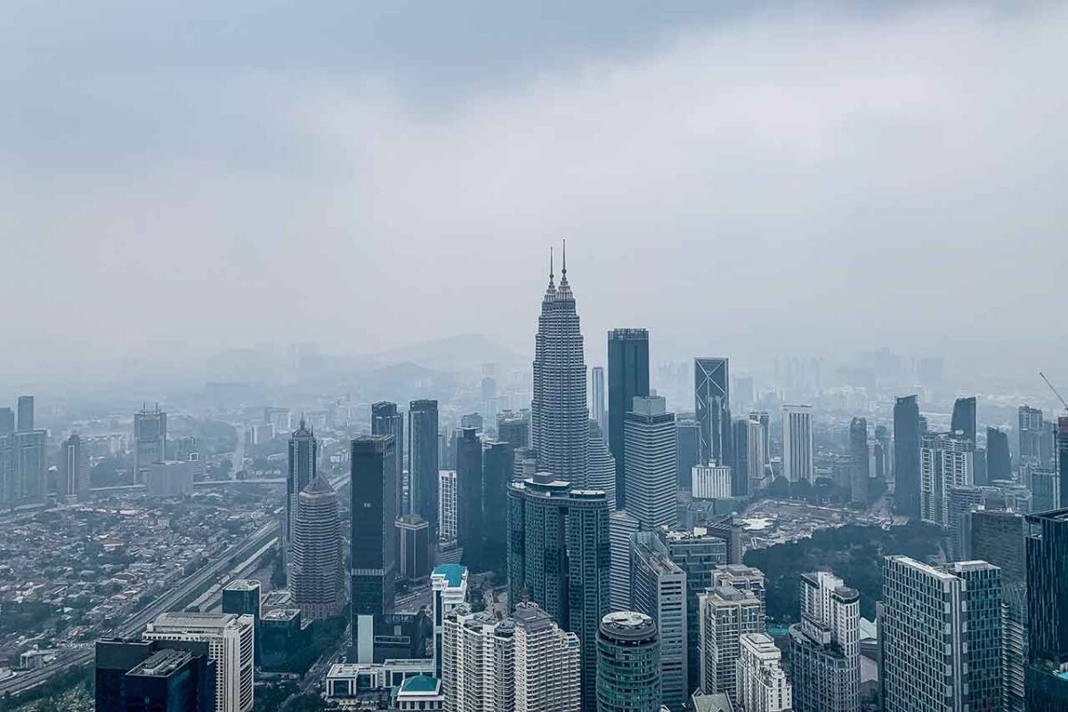 Widok na Petronas Towers z KL Tower to esencja Kuala Lumpur na jednym zdjęciu: ikoniczne wieżowce, które definiują skyline miasta, uchwycone w unikalnej perspektywie.