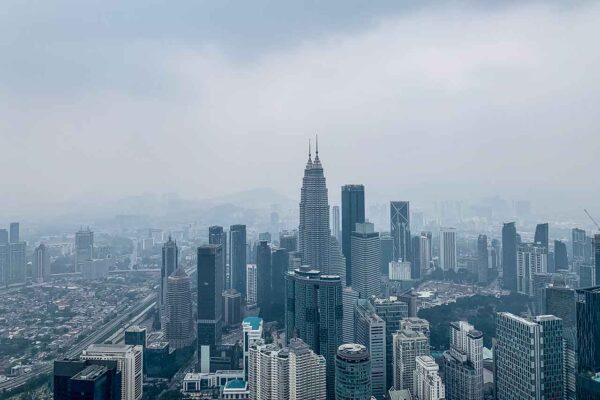 Widok na Petronas Towers z KL Tower to esencja Kuala Lumpur na jednym zdjęciu: ikoniczne wieżowce, które definiują skyline miasta, uchwycone w unikalnej perspektywie.