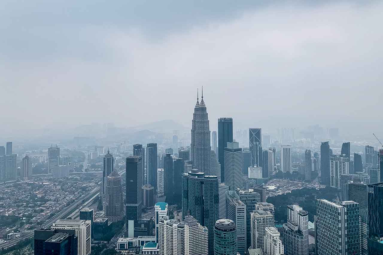 Widok na Petronas Towers z KL Tower to esencja Kuala Lumpur na jednym zdjęciu: ikoniczne wieżowce, które definiują skyline miasta, uchwycone w unikalnej perspektywie.