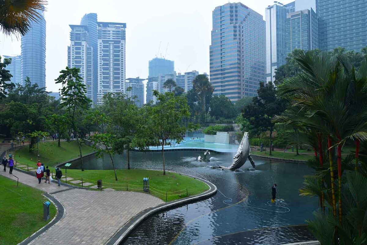 Widok na KLCC Park w Kuala Lumpur z alejkami, fontanną w kształcie wieloryba i panoramą wieżowców
