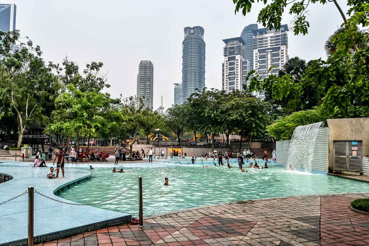 Widok na basen z wodospadem w KLCC Park w Kuala Lumpur, z wieżowcami w tle