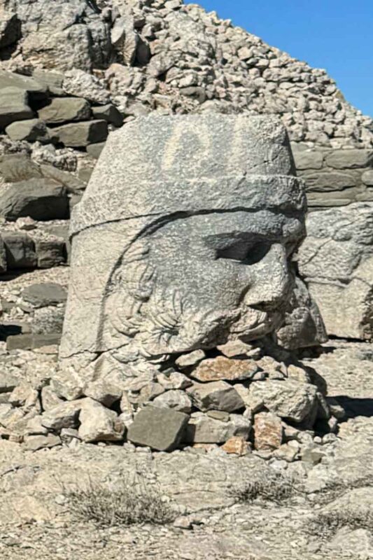 Monumentalny posąg Zeusa na Górze Nemrut w Turcji, będący synkretycznym połączeniem greckiego Zeusa i perskiego Ahura Mazdy, symbolizujący najwyższe bóstwo w starożytnym Królestwie Kommageny.