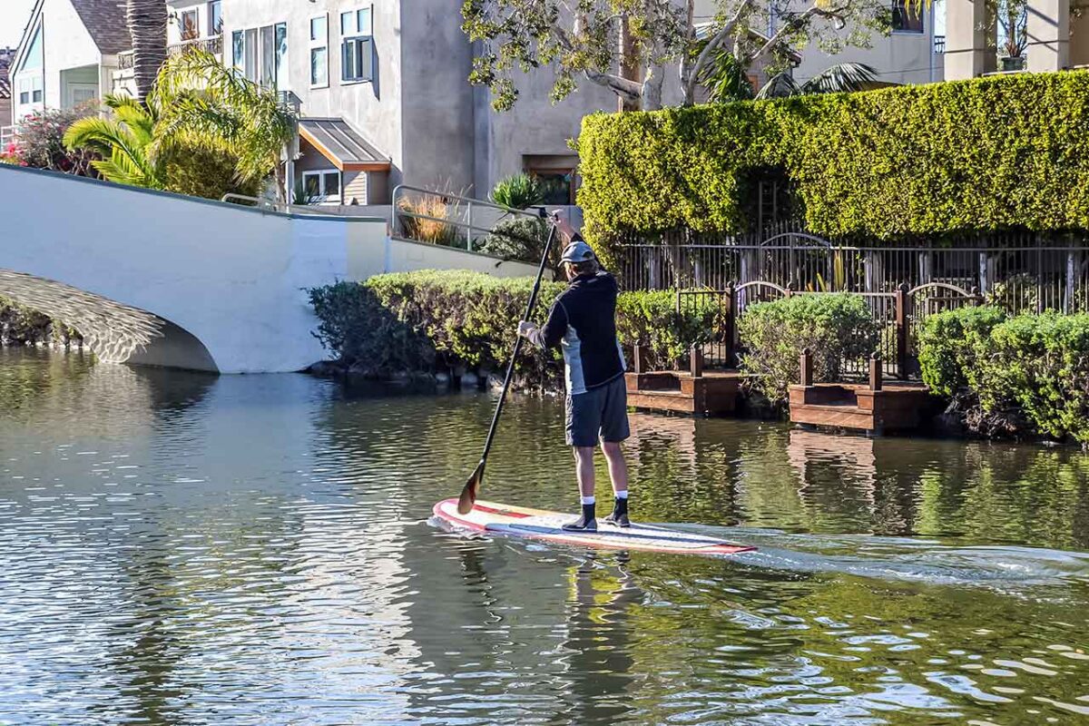 Uomo su tavola SUP nel canale a Venice Beach