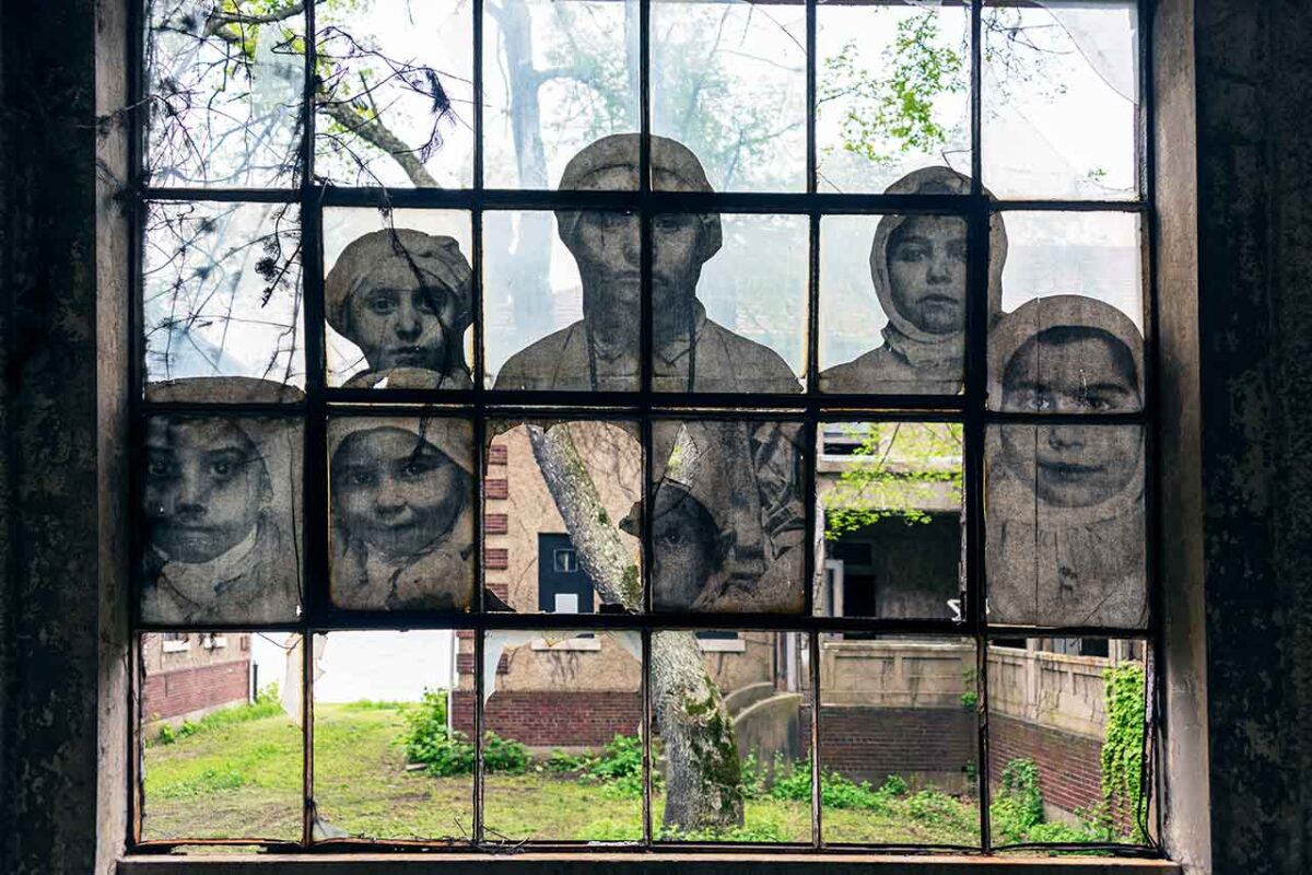 Ritratti di immigrati sui vetri dell’ex ospedale di Ellis Island.