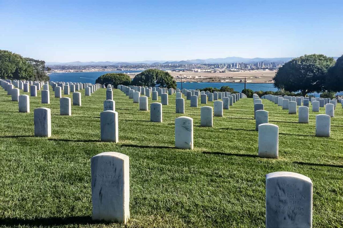 File di lapidi bianche al cimitero Fort Rosecrans con lo skyline e la baia di San Diego sullo sfondo