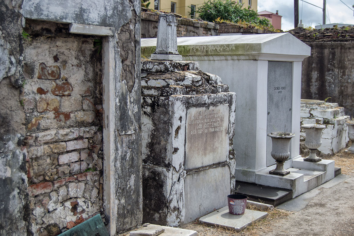 Tomba danneggiata accanto a una cripta restaurata allo St. Louis Cemetery No. 1.
