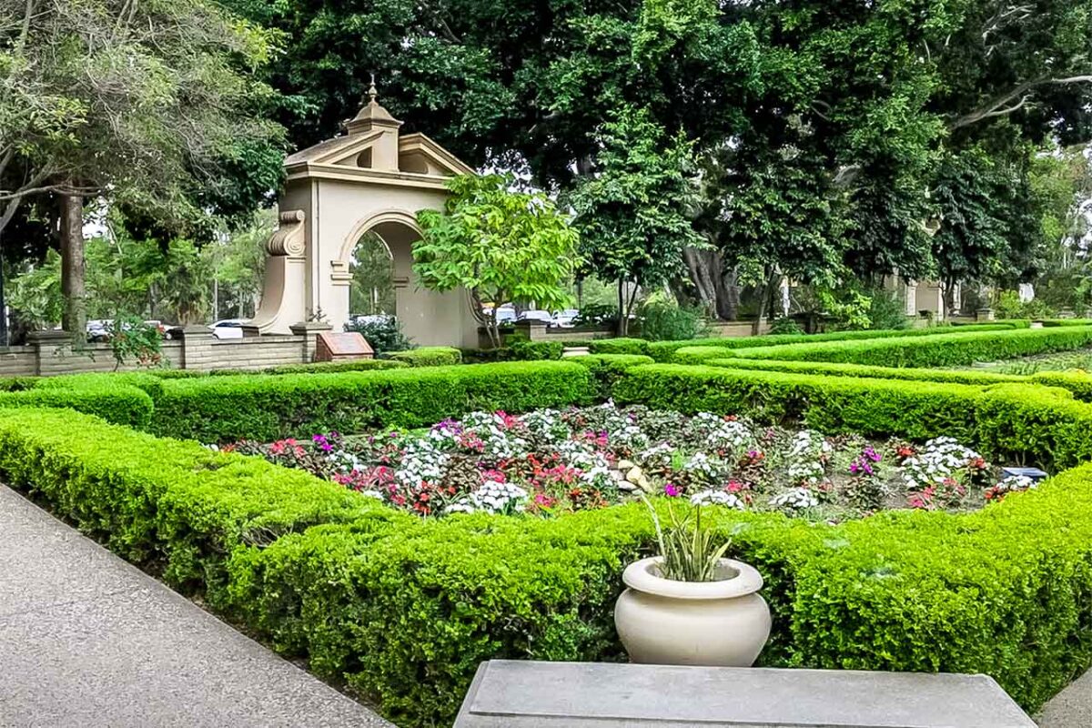 Veduta dell’Alcazar Garden a Balboa Park a San Diego – siepi geometriche, fiori colorati e portale decorativo sullo sfondo