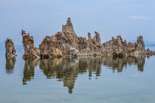 Tufowe formacje skalne w jeziorze Mono Lake w Kalifornii odbijające się w spokojnej tafli wody